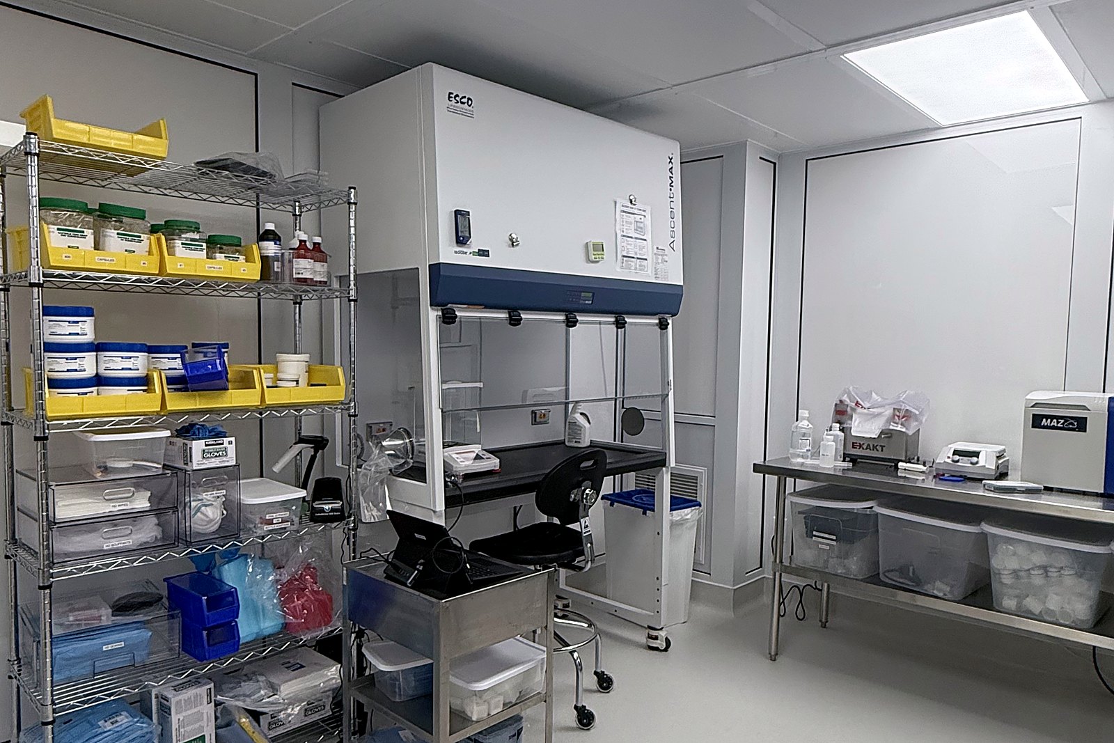 Hazardous drug compounding room with containment enclosure and stainless steel workbench