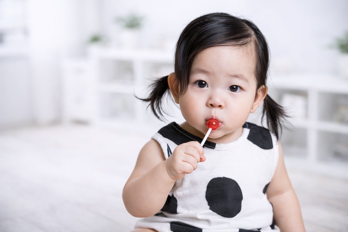 Toddler holding a red lollipop